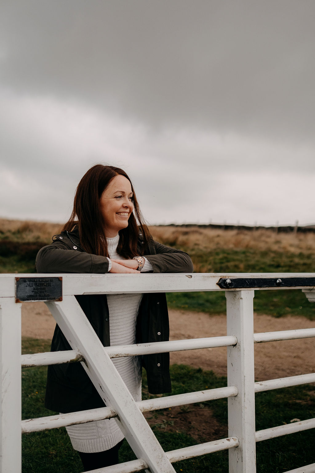 Caroline Stocks leaning against a white fence in the Peak District