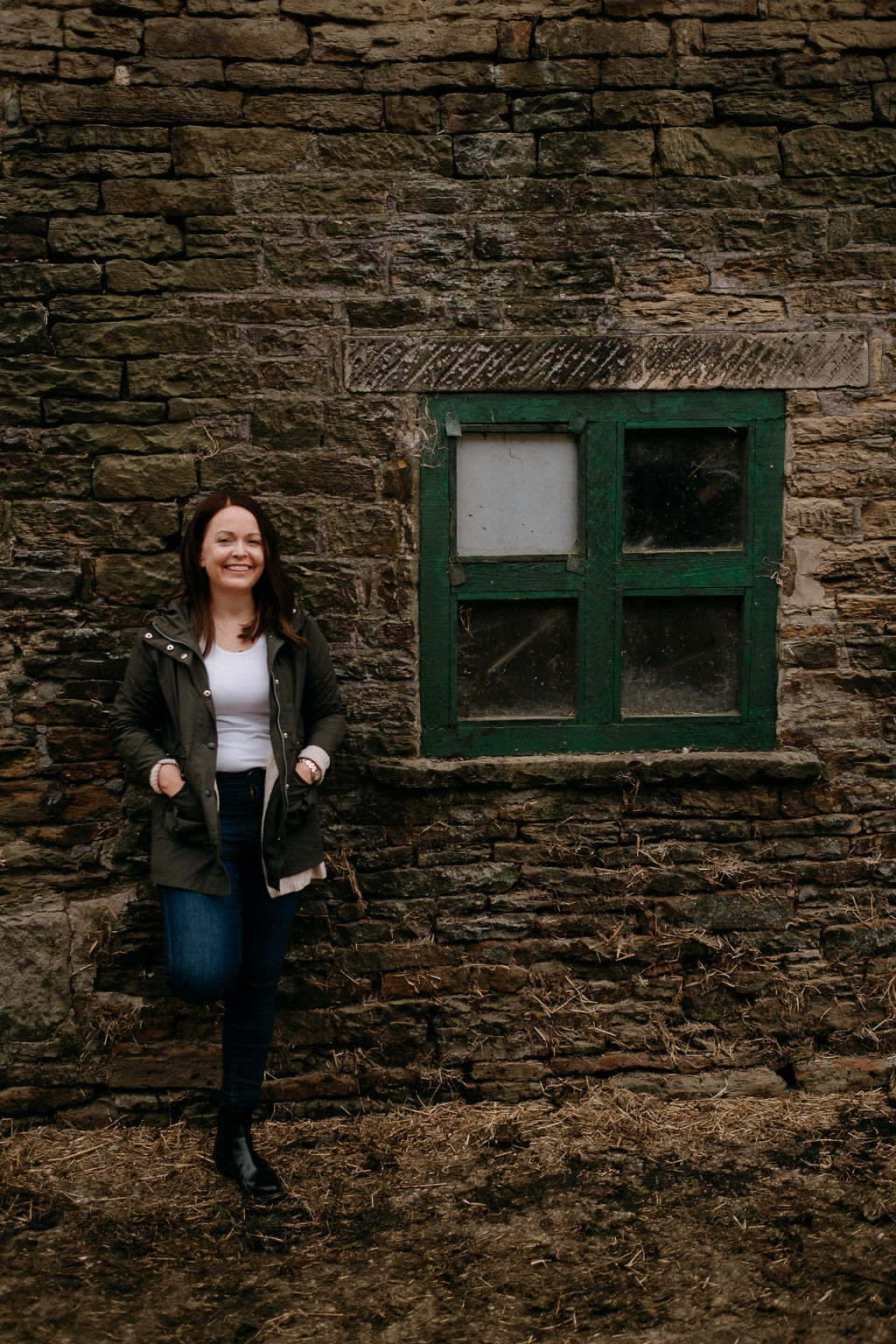 Caroline Stocks leaning against a brick outbuilding on a farm